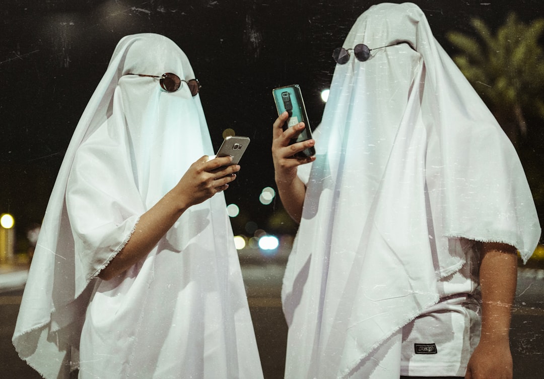 two people dressed in white are looking at a cell phone — Foto por Kevin Gil Musñgi na Unsplash
