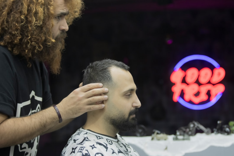 a man getting his hair cut at a barber shop — Foto por mostafa meraji na Unsplash