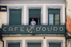 Man in window above cafe sign with anchor. — Foto por Anastasiia Mitiushova na Unsplash