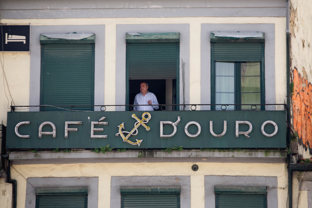 Man in window above cafe sign with anchor. — Foto por Anastasiia Mitiushova na Unsplash
