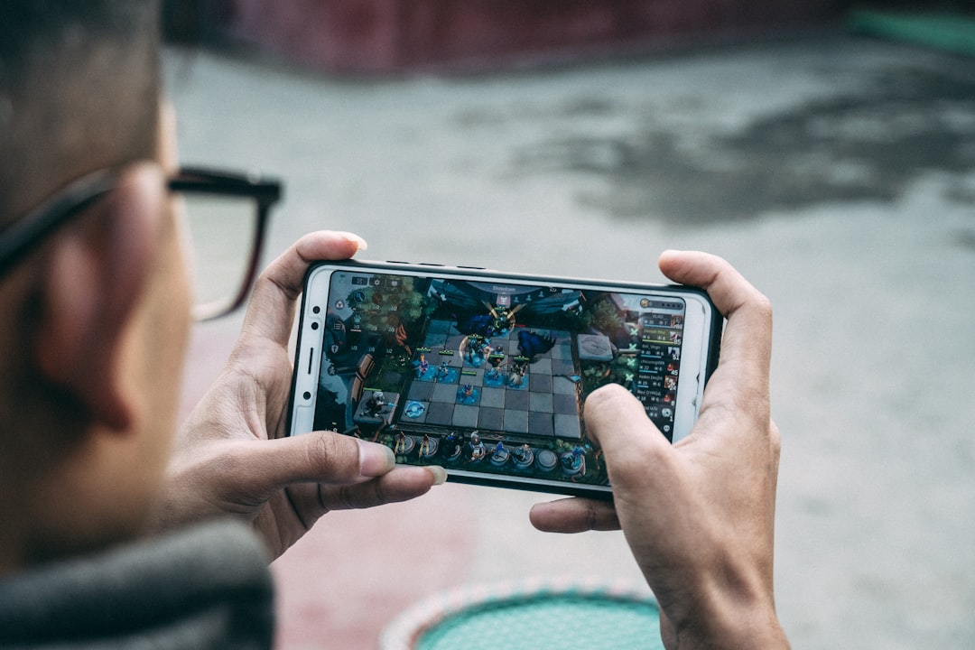 a man is playing a game on his phone — Foto por Leeder Bose na Unsplash