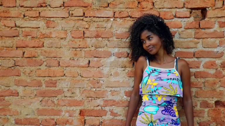 a woman standing in front of a brick wall — Foto por Eddie Santos na Unsplash