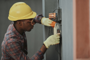 electrician installing wiring with yellow hardhat — Foto por Emmanuel Ikwuegbu na Unsplash