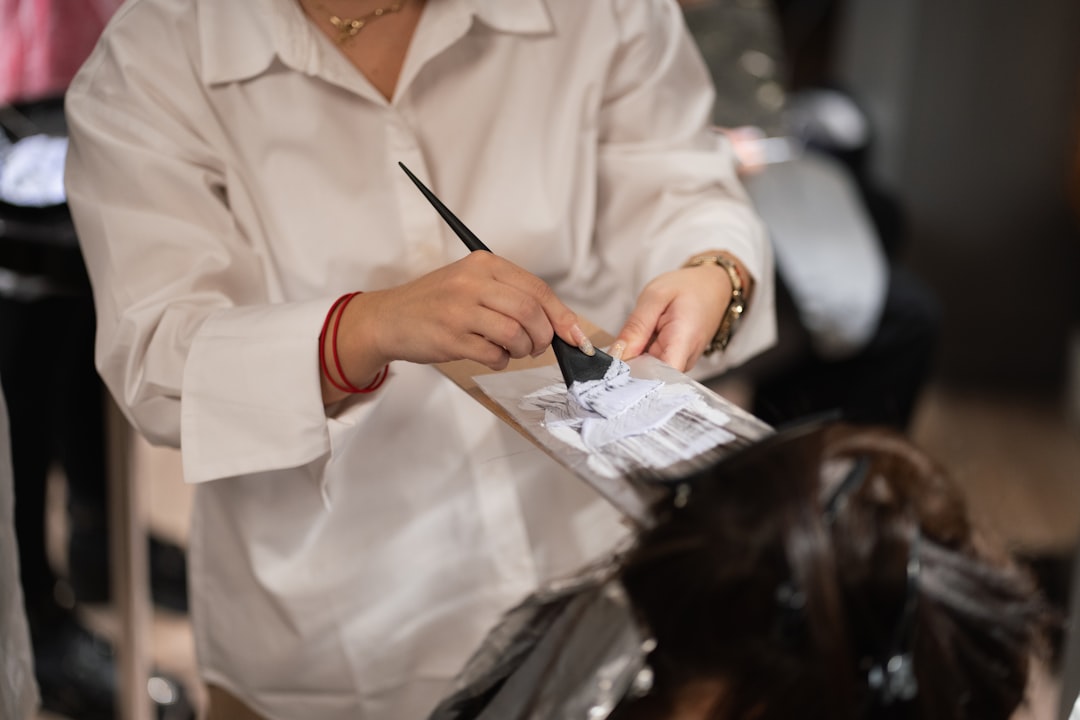 a woman cutting another woman's hair with a pair of scissors — Foto por Ionela Mat na Unsplash